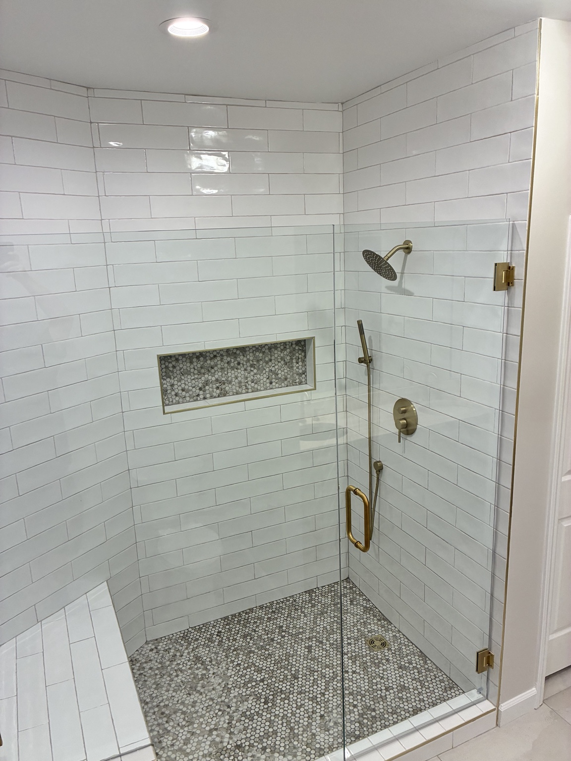 Finished custom shower with glass enclosure and brass fixtures