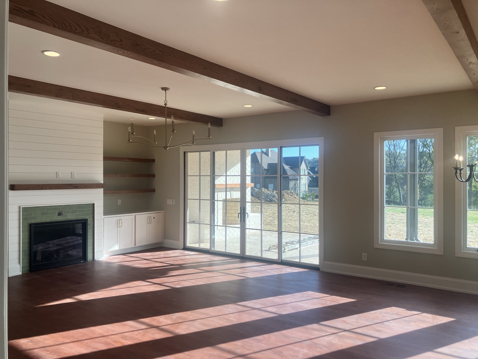 Finished living room with wood beams, fireplace, and large windows
